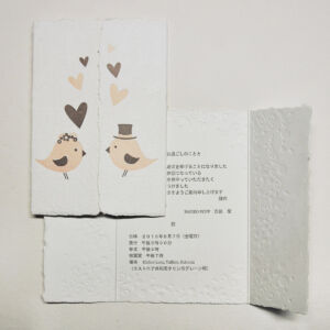 Letterpress printed wedding invitation with birds, hearts and flowers on handmade paper